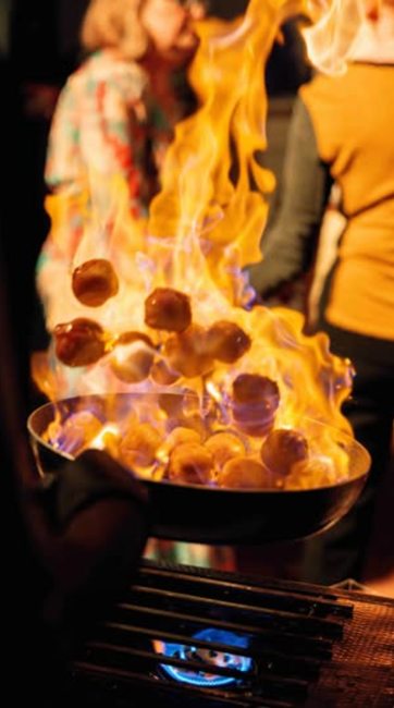 Dramatic flames rising from a pan at a live cooking station